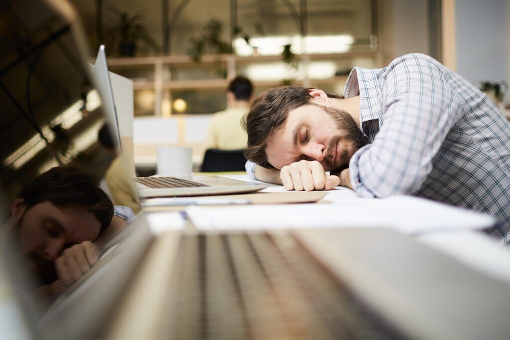un homme dort devant son ordinateur sur son bureau