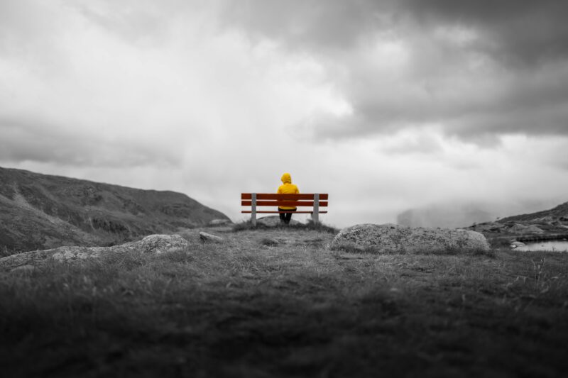Personne assise seule sur un banc illustrant le ralentissement et le retour à soi